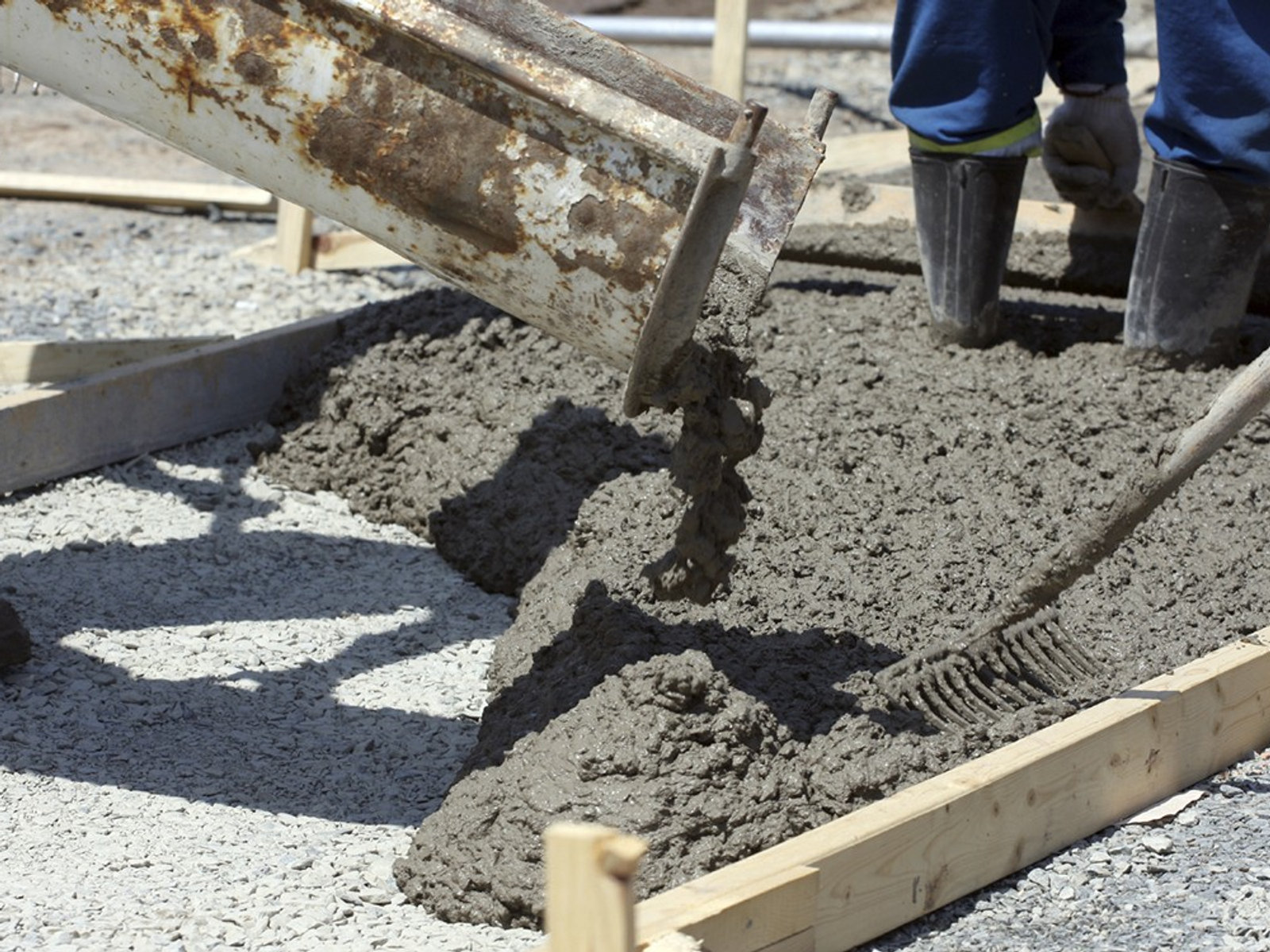 Crew placing wet concrete into a formed sidewalk section
